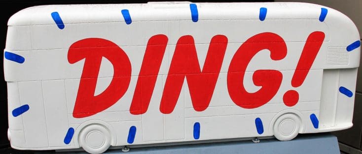 White bus-shaped display with the word “DING!” painted in bold red letters and blue accents, symbolizing MBA rejection.