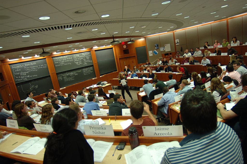 Harvard Business School students participating in a large classroom discussion, illustrating the academic environment and collaborative learning style of an MBA program.