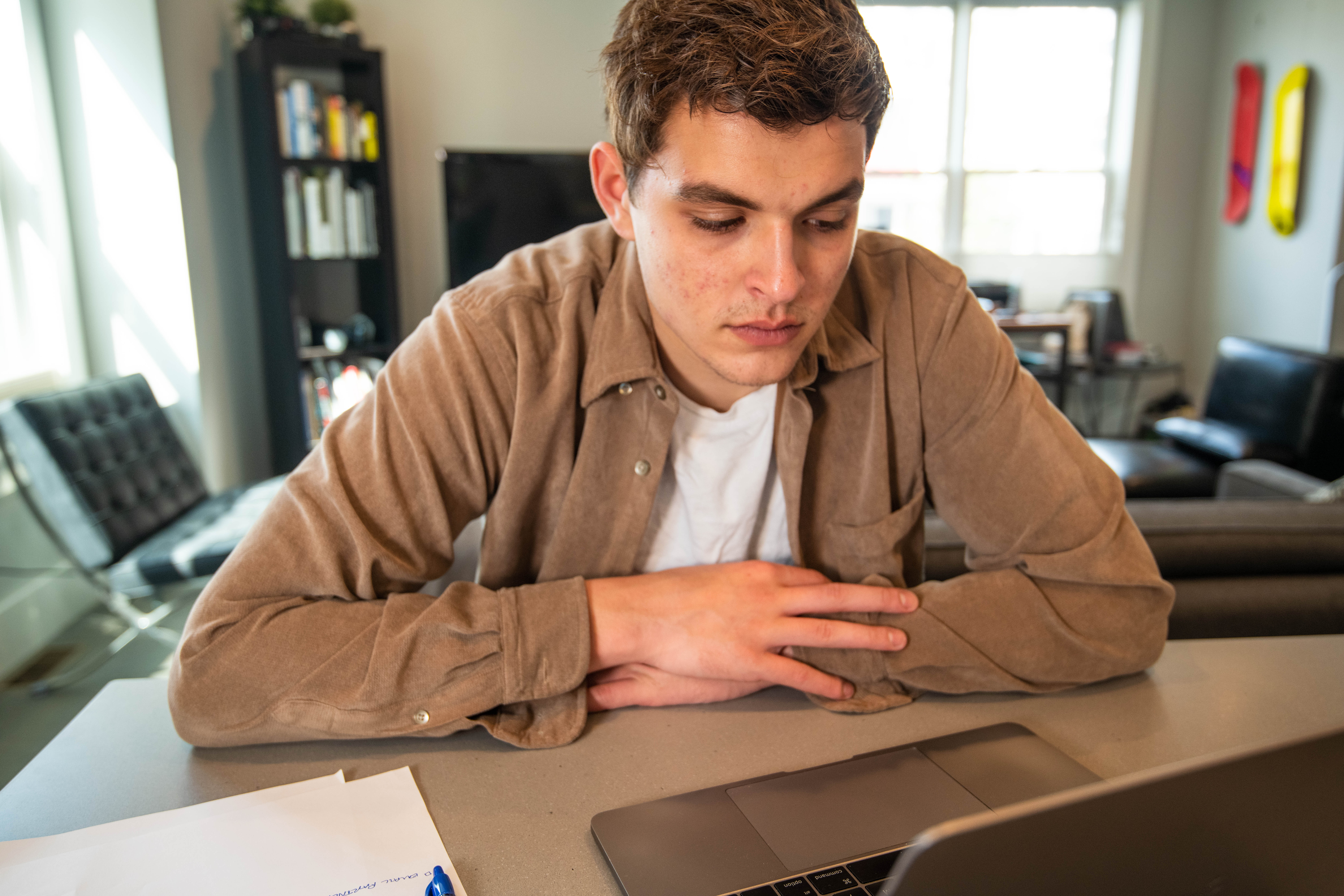 Business school applicant looking concerned while reviewing MBA recommender strategy on laptop.