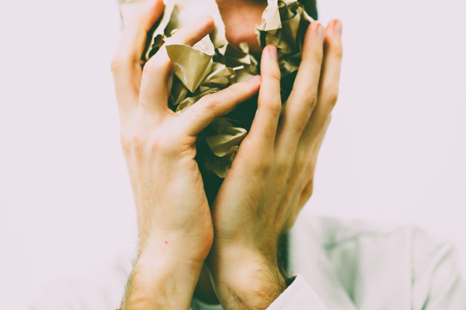 Stressed applicant covering face with crumpled paper, symbolizing MBA application stress and burnout.
