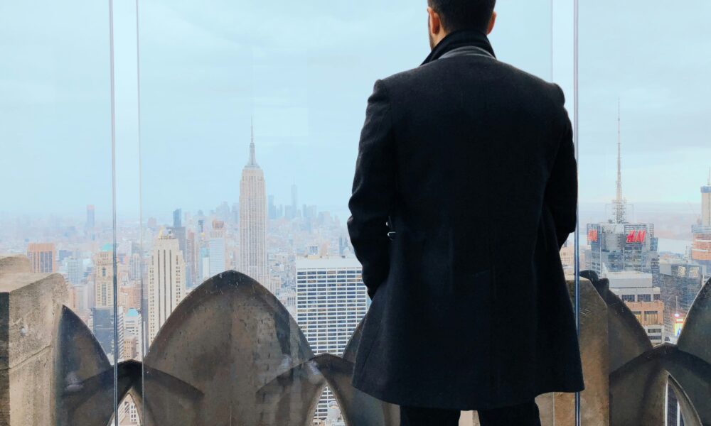 Man in coat overlooking New York City skyline, symbolizing ambition and forward-looking MBA leadership.