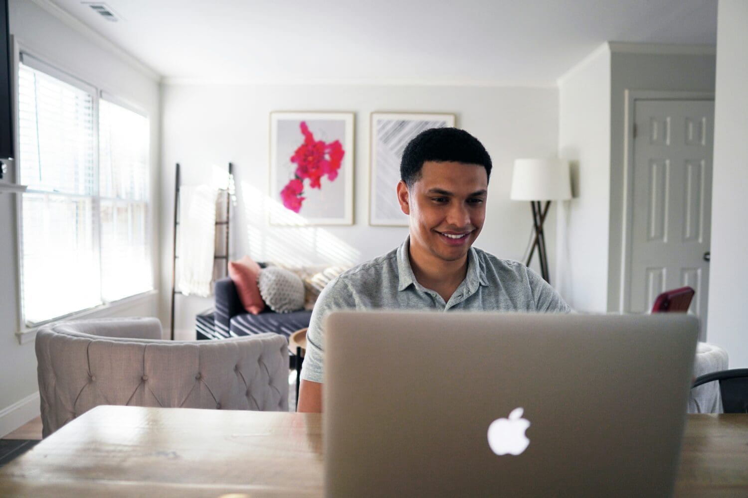 MBA applicant smiling while practicing video questions at home on a laptop, applying MBA video essay tips with confidence.