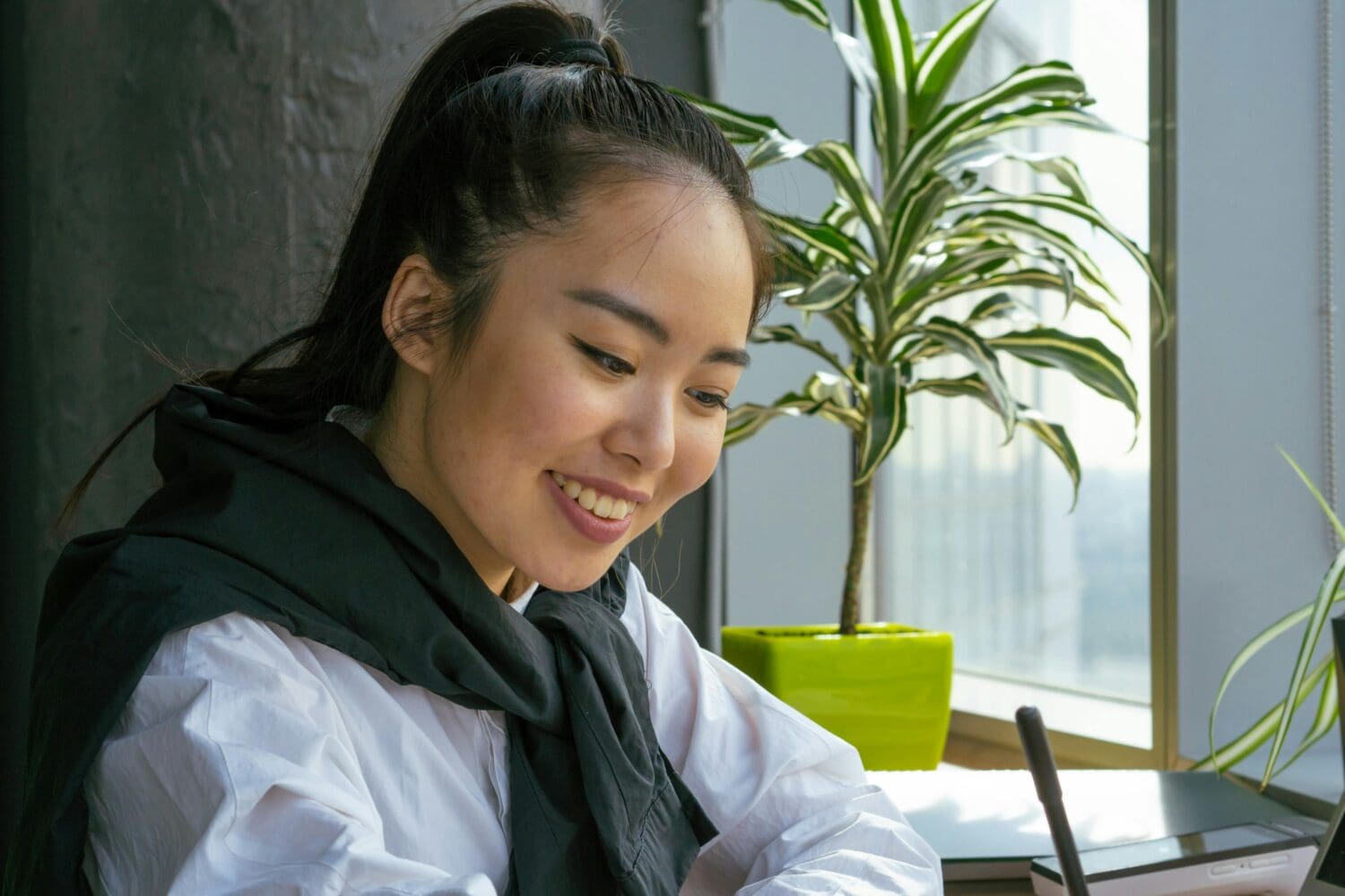 Smiling graduate student researching funding for your MBA on laptop in bright study space.