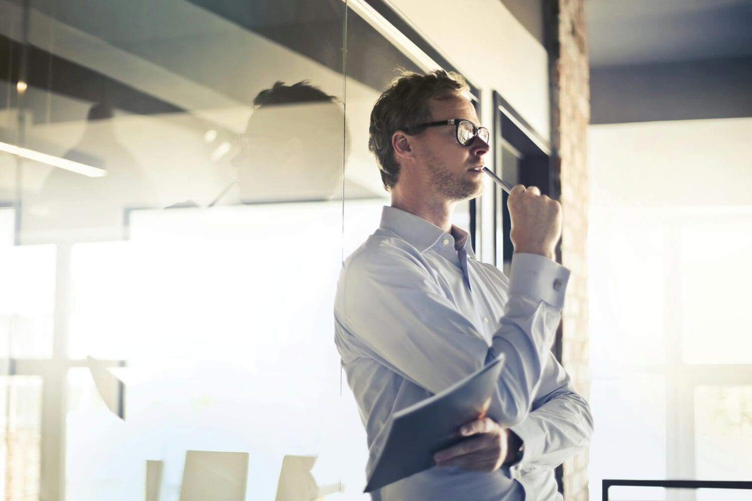 A professional weighing a job change before MBA applications, standing thoughtfully in a modern office.